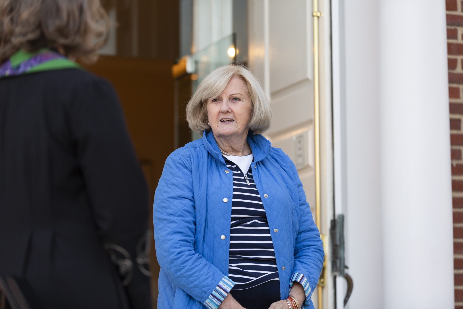 A woman greets a pastor at the church door