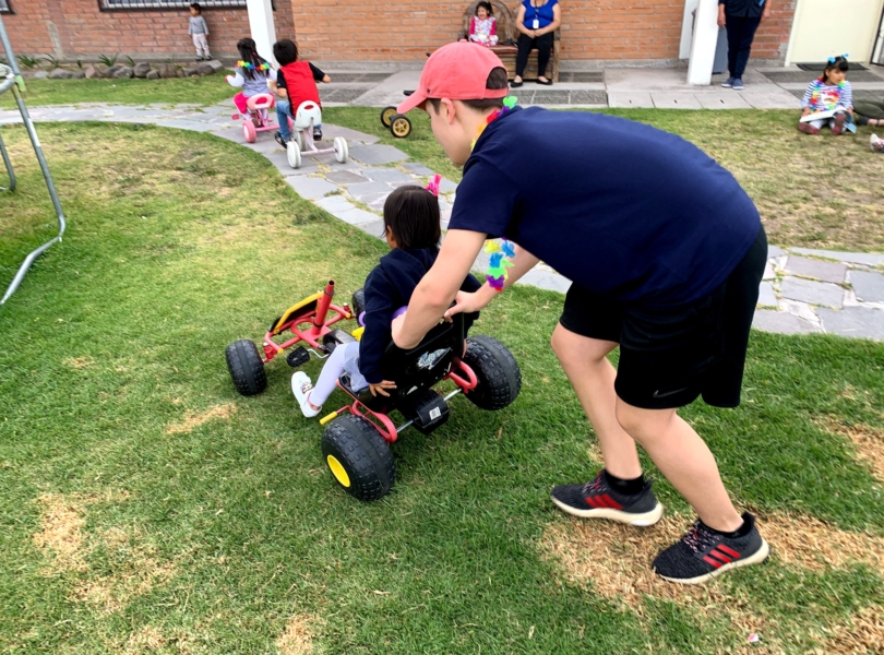 Youth pushes girl on tricycle